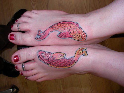 Due simili pesci colorati tatuati sui piedi della ragazza