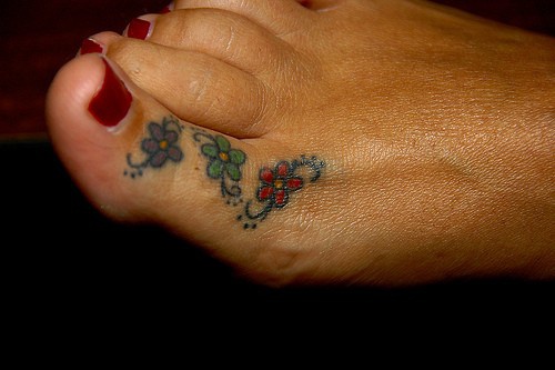 Three little flowers disposed on toe foot tattoo
