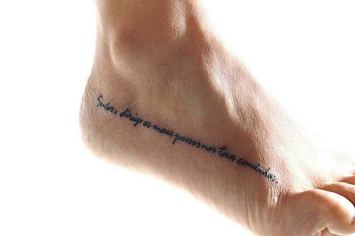 Long inscription , tiny letters along  foot tattoo