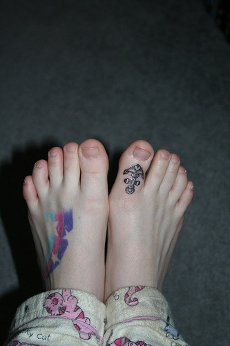 Tattoo von Sternen mit dem Regenbogen als Hinterhrund auf dem Fuß und Anker auf großem Zeh