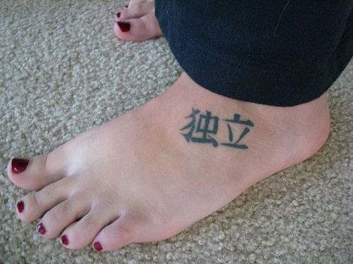 Two little dark  hieroglyphs foot tattoo