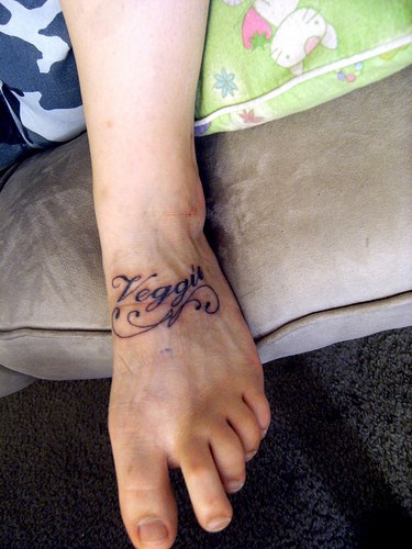 Veggu- curled style inscription foot tattoo design