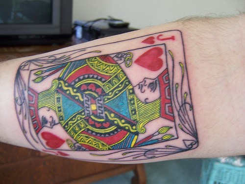 La carta da gioco il re di cuori tatuata sul braccio