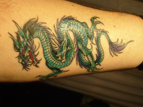 Tatuaje en el antebrazo, diseño de color radiante verde, dragón con orejas largas