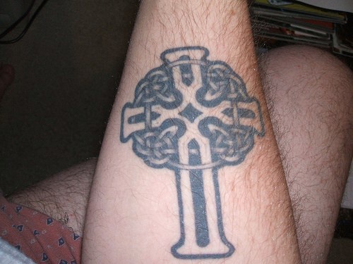 Grande croce nera tatuata sul braccio
