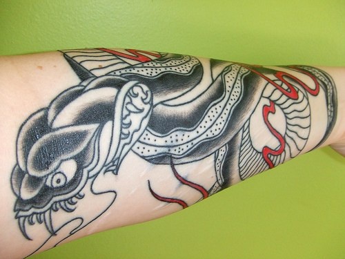 Evil viper with sharp teeth forearm tattoo