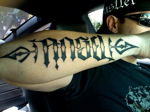 Ambigramma con la parola tatuato sul braccio