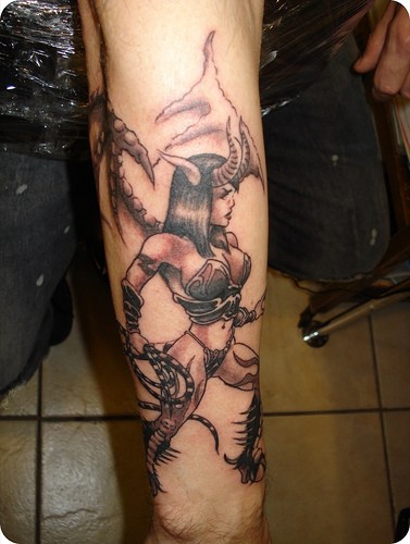 Cruel horned woman with whip forearm tattoo