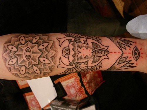 Tatuaje en el antebrazo, insecto, objeto de forma ronda, descolorido