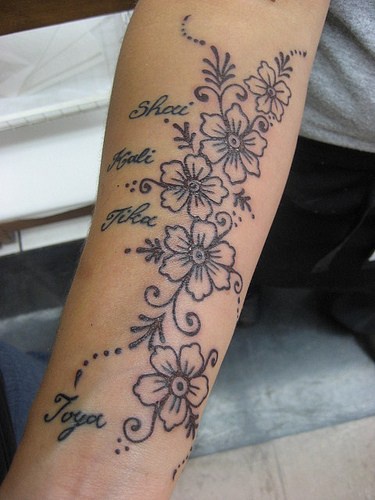 La fila dei fiori e nomi tatuati sul braccio