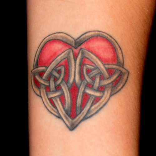 Tatuaje en el antebrazo, corazón rojo puesto en una jaula de hierro