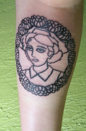 Ritratto della donna non colorato tatuato in forma rotonda sul braccio