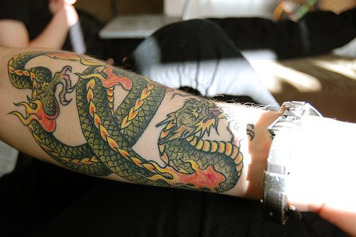 Tatuaje en el antebrazo, dragon verde largo envuelto en la mano - Tattooimages.biz