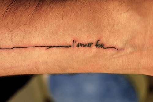 Uneven seam with french inscription  forearm tattoo