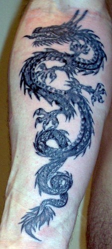 Le tatouage avant-bras d&quotun dragon noir cornu en colère
