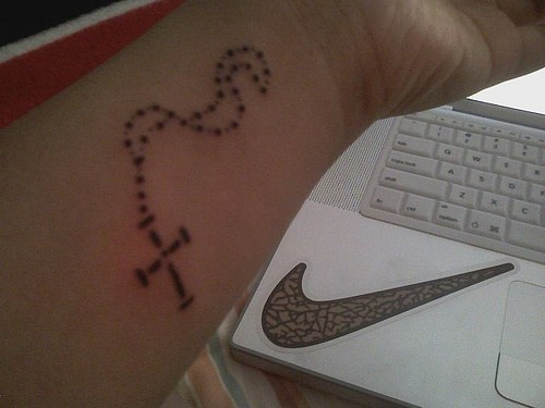 Une petite chaîne noire le tatouage avant-bras avec un croix