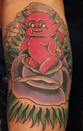 Tattoo von kleinem rotem listigem Teufel in lila  Rose am Unterarm