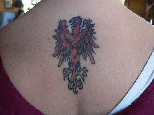 el tatuaje pequeño de la ave fenix de color rojo hecho en la espalda