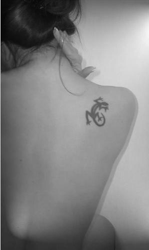 El tatuaje tribal de una lagartija pequeña en color negro en el hombro