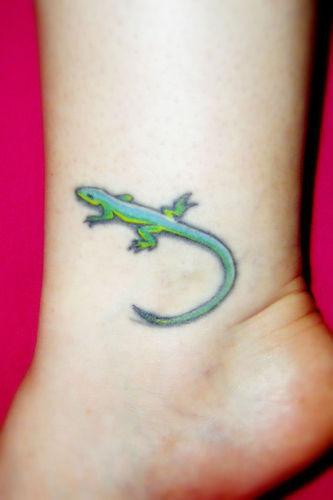 El tatuaje chicho de una lagartija de color verde en la pierna