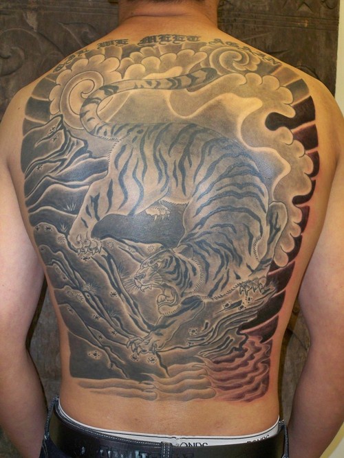 Un gros tatouage sur le dos avec un tigre asiatique marchant à pas de loup