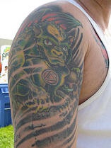 tatuaje  en el hombro gárgola verde con el collar de triángulo