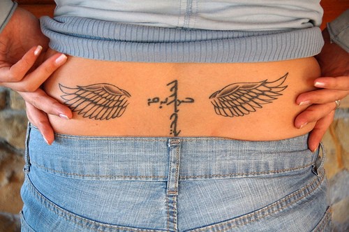 tatuaje en el bajo de la espalda de cruz y alas