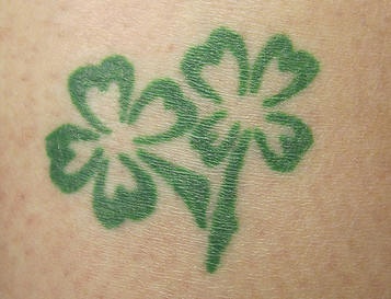 Two green four leaf clovers tattoo