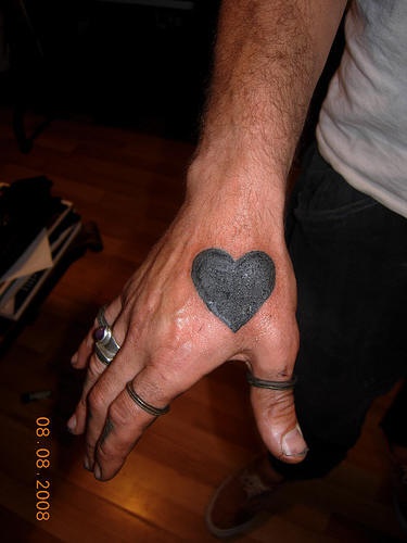 Grande cuore nero tatuato sulla mano