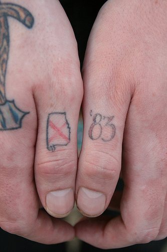 Tattoo von kleinem Zeichen und Zahl an Daumen