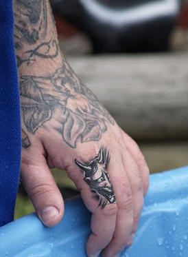 Grande angelo non colorato tatuato sulla mano e piccolo diavolo tatuato sul dito