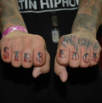 Tattoo von farbiger stilisierter Inschrift &quotStr8 edge" an der Hand