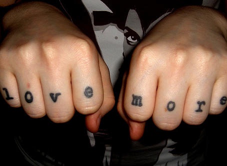 Love more, inscription on fingers hand tattoo