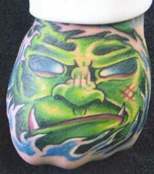 Tatuaje en la mano, monstruo verde con colmillos, en ondas