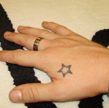 Piccola stella nera tatuata sulla mano
