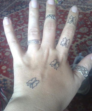 Tatuaje en la mano, cuatro mariposas similares descoloridos