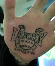 Tattoo &quotLucky bail bonds"  mit Hufeisen und Kode in Schwarz an der Handfläche