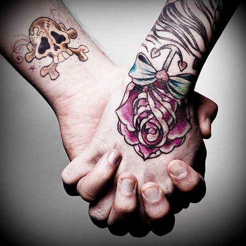 Tatuaje en la mano, rosa con una ancla pequeña, calavera