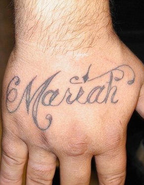 Tattoo von stilisierter verschnörkelter Inschrift &quotMariah" an der Hand