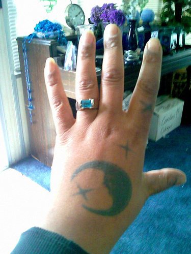 Tattoo von feinem Mond und stilisierten Sternen an der Hand