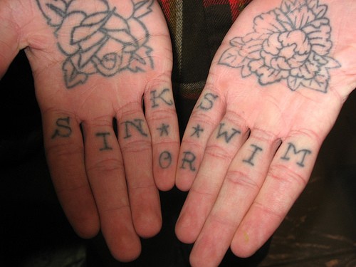 Une inscription Coule ou nage avec le tatouage de rose et de buisson sur la main