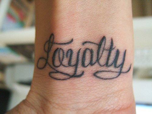 Calligraphic tattoo with word Loyalty on inner side of hand