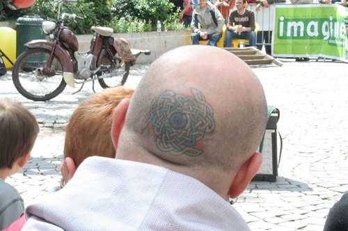 Head tattoo with round object of chains and eye