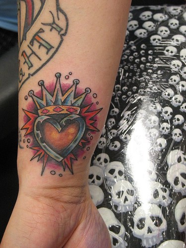 tatuaje en color en la muñeca de corazón coronado