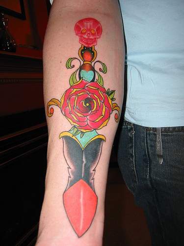 Surreal red rose dagger arm tattoo
