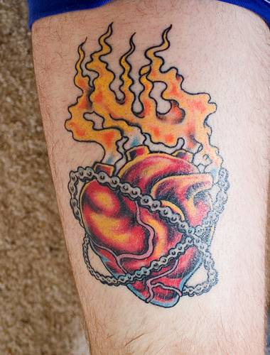 tatuaje de corazón con llamas en cadenas