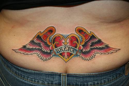 tatuaje en el bajo de la espalda de corazón dorado con alas
