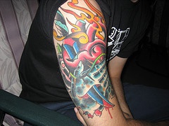 Le tatouage de cœur avec un poignard colorés en flammes