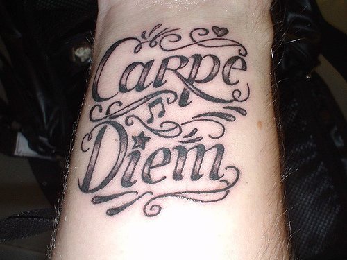 Le tatouage sur le poignet avec l'inscription calligraphique carpe diem
