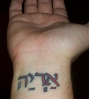 Red ink hebrew wrist tattoo